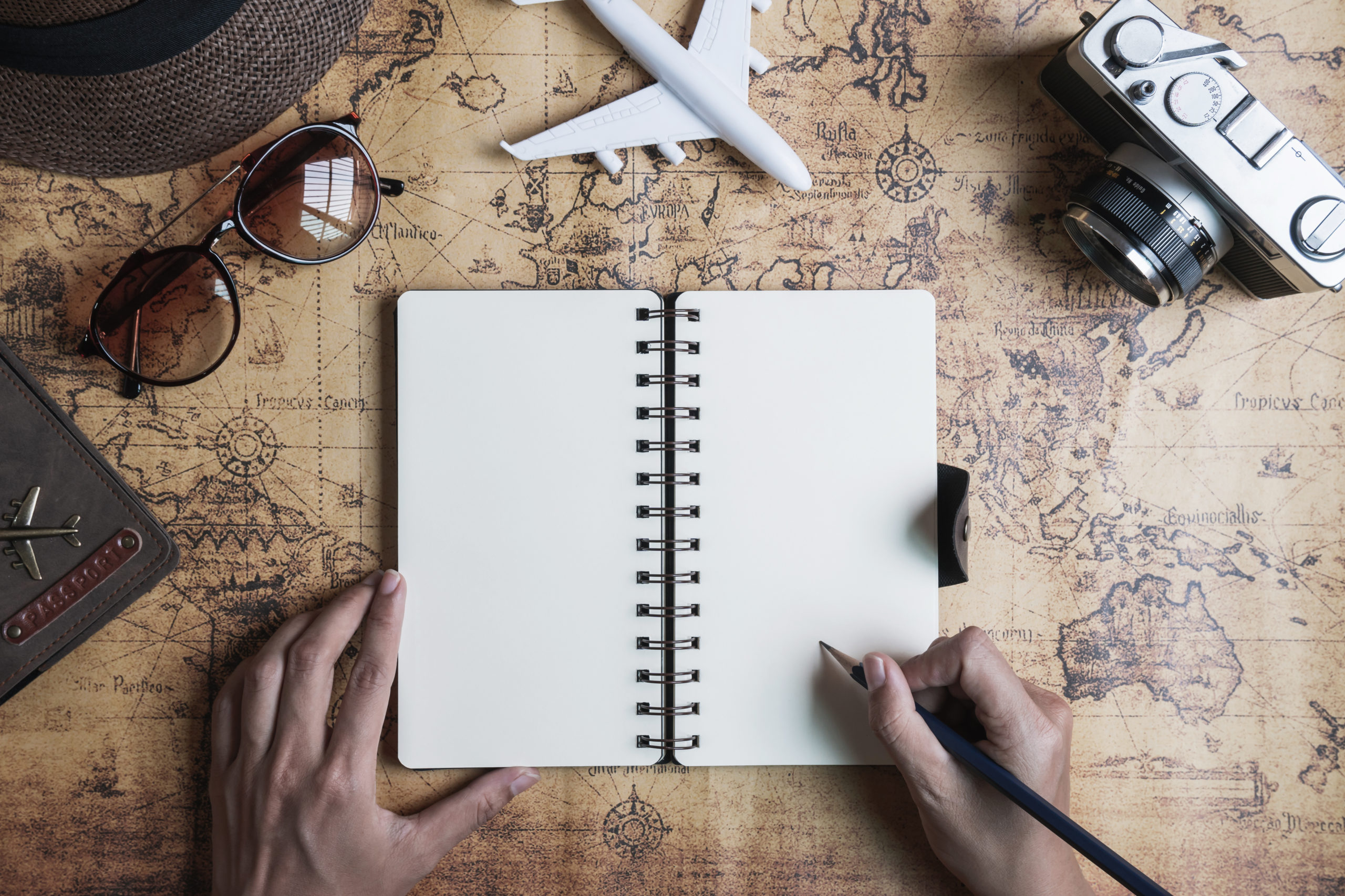 Retro camera with toy plane and travel dairy on old world map background with copy space, Travel concept